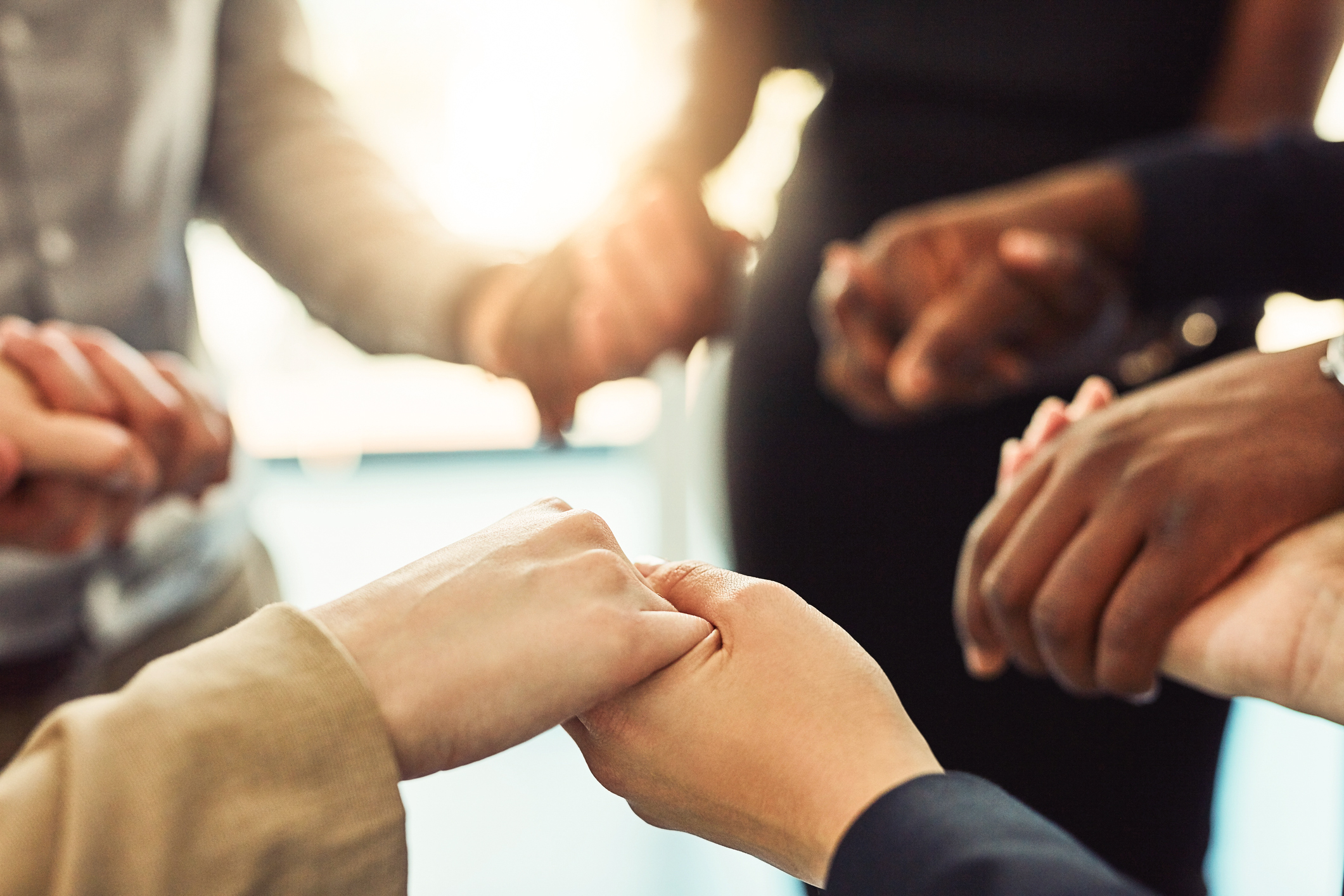 A group of people with various skin tones hold hands in a circle.